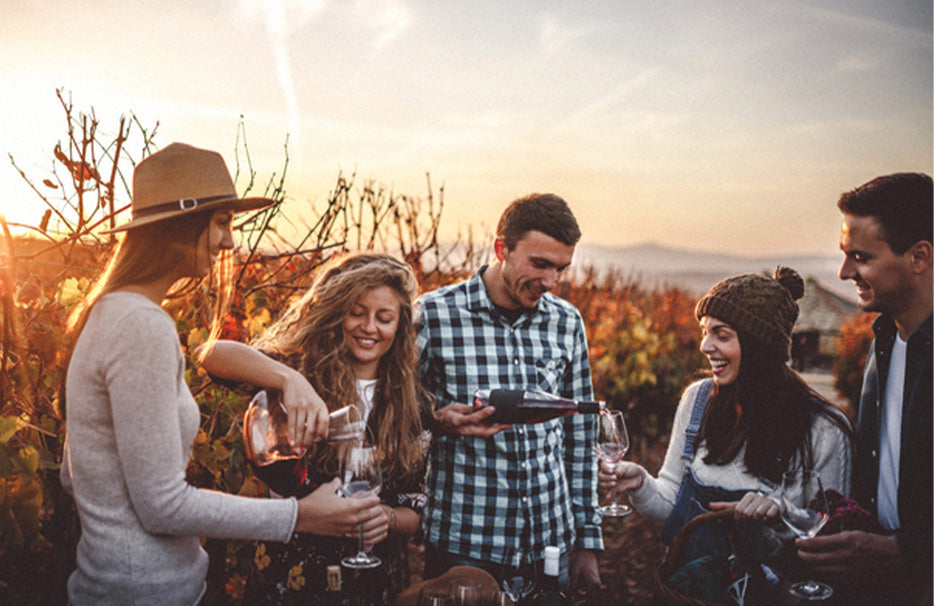 Herbstlicher Weinberg mit lachenden Menschen, die sich Wein einschenken